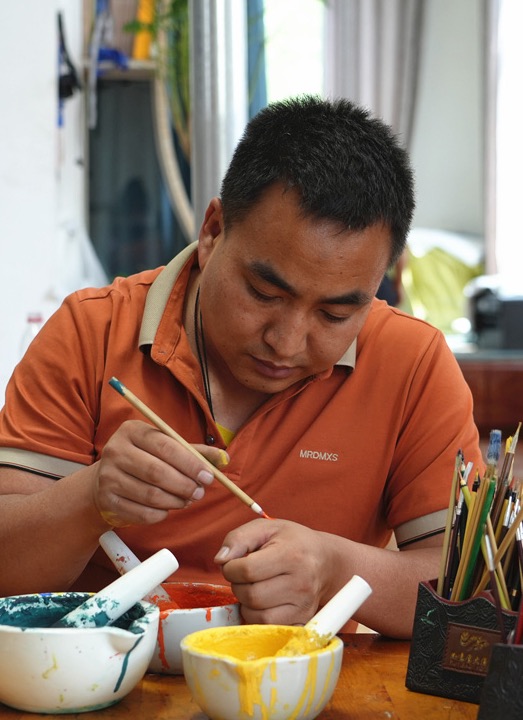 桑杰加國家一級美術師查看詳情行進中國︱指間生金 藝澤熱貢遠處雪山巍峨綿延，近處溪流蜿蜒、水草豐茂，大國非遺工匠、國家一級美術師桑杰加正在為一幅山水唐卡描繪鬆柏元素，細如針尖的畫筆反復描繪之后，一棵鬆樹躍然布上，盡管鬆樹很小，不是整幅畫作的核心元素，但桑杰加依舊反復描繪，精雕細琢，力求把鬆樹的細枝末節全都完美呈現，一筆一畫，都蘊藏著他對生活的感悟，對家鄉的熱愛，對藝術的追求。